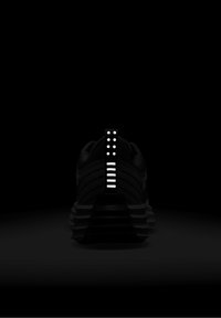 Svart sportskor med texturerad ovandel, utrustad med en reflekterande hälflik med horisontella och vertikala vita ränder.