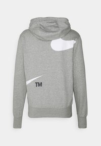 Grå hoodie med en stor vit grafik och svart "TM"-text på ryggen. Mjuk tyg med dragsko i huvan och ribbade manschetter.