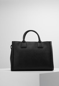 Musta nahkalaukku, jossa on kaksi ylhäältä kantavaa kahvaa, rakenteellinen suorakulmainen muoto, teksturoitu pinta ja minimalistischinen muotoilu, asetettuna valkoiselle jalustalle.