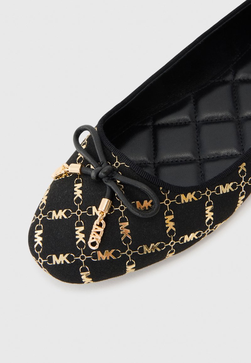 Scarpa piatta nera con interno trapuntato, caratterizzata da un motivo a catena dorata e dettagli con logo. Include un fiocco e dettagli in oro.