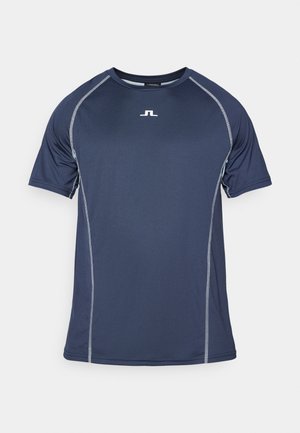Tumši zils sporta T-krekls ar īsām piedurknēm, kontrastējošām pelēkām šuvēm un mazu logo uz krūtīm. Izgatavots no mitruma novadošiem materiāliem.