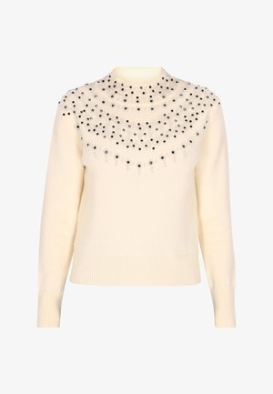 Maglione a collo alto color crema con lavorazione a punto grosso. Parte superiore decorata con applicazioni nere e trasparenti di varie dimensioni. Polsini e orlo a coste.