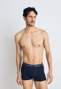 Marine boxer-truser laget av bomull med en tettsittende design, som har en merket elastisk midje og en glatt tekstur.