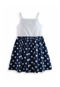 Robe sans manches avec un haut en coton blanc et une jupe bleu marine ornée de grands pois blancs, froncée à la taille pour plus de volume.