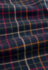 Tessuto di lana blu navy con motivo a quadri con linee rosse, verdi e arancioni. Tessitura morbida con dettagli evidenti.