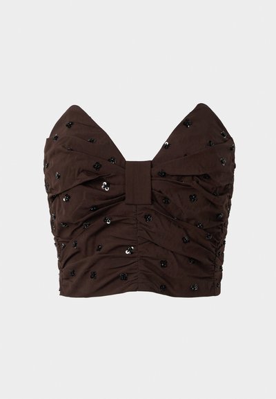 Smeđi top bez naramenica s dekolteom u obliku srca, naboranom tkaninom, ukrašen crnim šupljikama i cvjetnim detaljima.