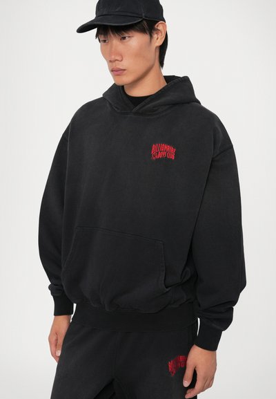 Sudadera negra con capucha y gran bolsillo frontal, puños y dobladillo de canalé. Presenta el texto bordado en rojo "Billionaire Boys Club" en el pecho.