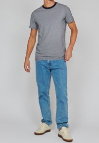Grau gestreiftes T-Shirt mit marineblauem Rundhalsausschnitt, kombiniert mit hellblauen Denimjeans und cremefarbenen Sneakers. Einfaches und lässiges Outfit.