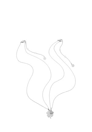 Two silver necklaces with thin chains, each featuring a four-leaf clover pendant and a small clover charm near the clasp.