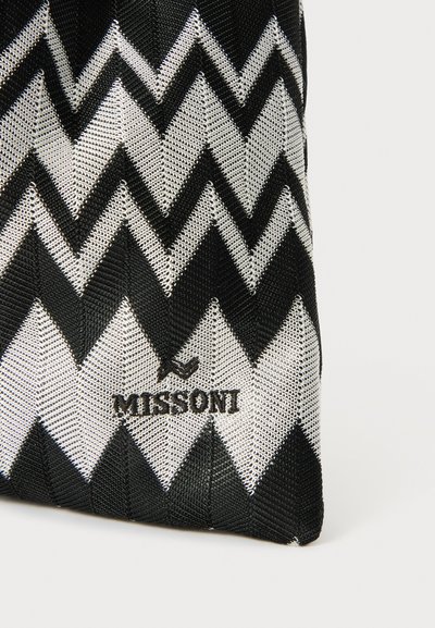 Fekete-fehér cikk-cakk mintájú táska texturált felülettel és fekete "Missoni" logóval az egyik oldalon. Kompakt téglalap alakú.