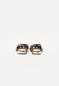 Sandali neri con accenti metallici, caratterizzati da un design a fascia larga e un tacco blocco basso. La soletta è color marrone chiaro e liscia.