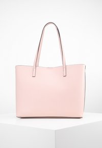 Roze leren tote bag met twee lange handvatten. Soepele textuur, gestructureerde vorm en contrasterende zwarte rand langs de bovenkant. Minimalistisch ontwerp.