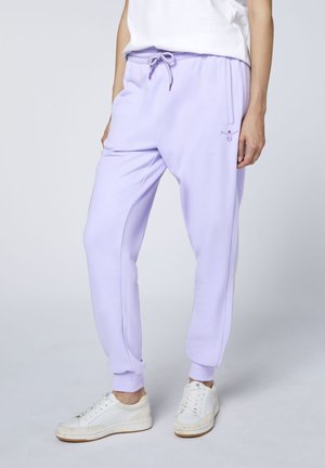 Person wearing light purple jogger pants with side pockets and a drawstring waist, paired with white sneakers and a white top.