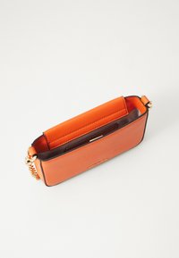 Orange läderkuvert med en slät yta, strukturerad form, guldhandtag och öppen topp, med en kontrasterande mörk inredning.
