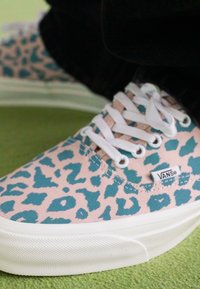 Vans sneakers with a pink canvas upper featuring a teal leopard print, white laces, and a textured white rubber sole.