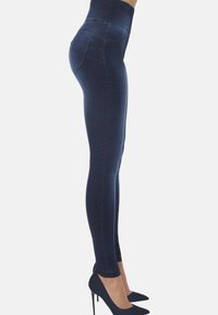 Legginsy o wysokim stanie w ciemnoniebieskim kolorze, wykonane z elastycznego denimu, z gładkim wykończeniem i tylnymi kieszeniami, stylizowane z niebieskimi czółenkami w szpic.