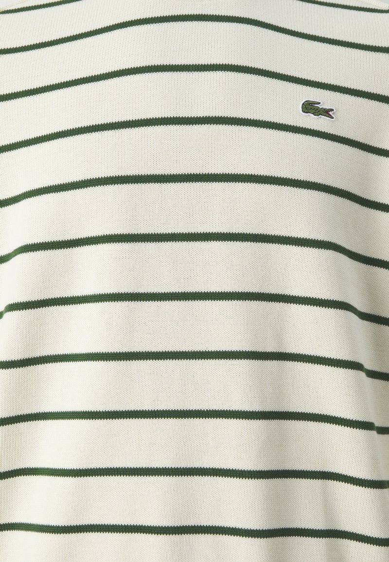 Suéter de manga corta a rayas en crema con rayas verde oscuro. Presenta un tejido texturizado y un pequeño logotipo bordado en el pecho.