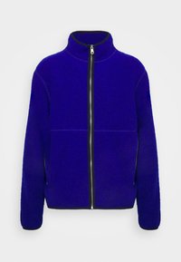 Zapinana polarowa kurtka w intensywnym niebieskim kolorze, z wysokim kołnierzem, czarnym zamkiem błyskawicznym i mankietami, o gładkiej fakturze i jednolitym wzorze.