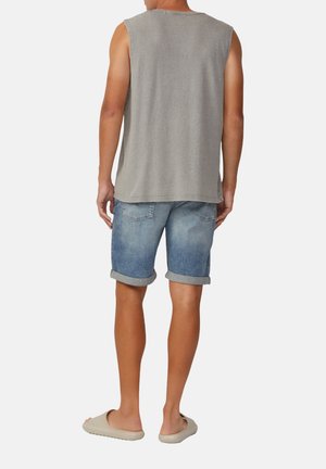Camiseta gris sin mangas, pantalones cortos de mezclilla azul claro con dobladillos enrollados y zapatillas beige de tipo slip-on. Diseño simple, apariencia casual.