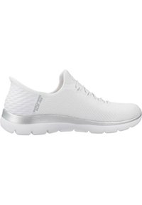 Basket de sport blanche avec une tige en maille respirante, un talon texturé et un accent argenté autour de la semelle. Présente un design flexible et rembourré.