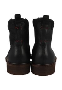 Botas de cuero negro hasta el tobillo con un acabado texturizado, suelas de goma marrón y costuras rojas contrastantes en el talón y los acentos del lazo trasero.