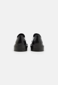 Black leather shoes with a glossy finish, rounded toe, and flat sole. Features minimal branding on the heel. Classic lace-up design.