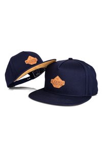 Navy blue cap with a flat brim, featuring a tan leather badge labeled "BLACKSKIES." Constructed from fabric with a smooth texture.