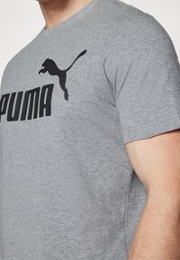 Grå bomulds T-shirt med et sort Puma-logo og tekstdesign. Korte ærmer, rund hals og glat tekstur.