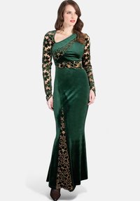 Grünes Samtkleid mit langen Ärmeln, goldenen floralen Spitzenakzenten, enganliegendem Oberteil und ausgestellt Rock. Auffälliger seitlicher Schlitz mit Spitzendetail.
