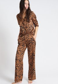 Conjunto de pijama de estampado de leopardo marrón con un corte relajado, que incluye una camisa abotonada y pantalones a juego, hecho de un tejido suave, con mangas largas.