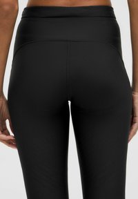 Leggings negros hechos de un tejido suave y elástico con una cintura alta. Presentan patrones texturizados sutiles a lo largo de las piernas y costuras planas.
