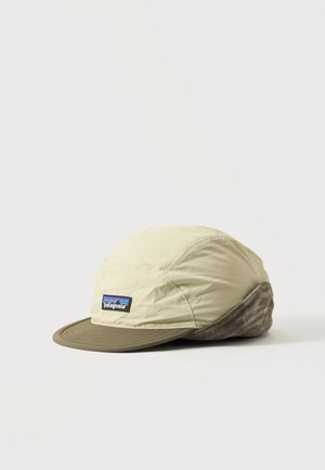 Gorra beige y oliva con orejeras forradas de forro polar y un parche con el logotipo de Patagonia en el panel frontal, mostrada sobre un fondo blanco.