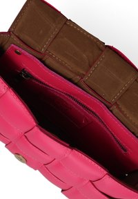 Borsa in pelle rosa con un design trapuntato e una texture liscia. L'interno presenta una fodera in tessuto marrone e una tasca con zip.