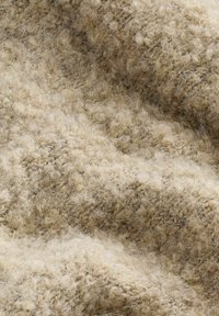 Lys brun tekstureret stof med et fluffy, blødt udseende, der har en blanding af fine og grove fibre, hvilket giver det et varmt og hyggeligt udseende.