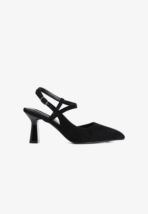Escarpin en suède noir avec un bout pointu et un talon épais et brillant. Présente des brides croisées à la cheville pour un meilleur soutien.