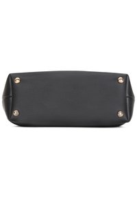 Vue de dessous d'un sac à main en cuir noir avec quatre pieds ronds en métal doré sur fond blanc.