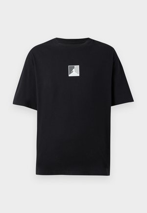 Black cotton t-shirt with a round neckline, featuring a white square logo with a silhouette in the center. Short sleeves, relaxed fit.