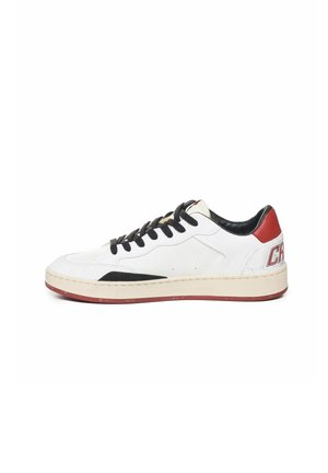 Sneaker in pelle bianca con accenti neri, punta testurizzata e dettaglio rossi sul tallone. Presenta lacci rotondi e una suola spessa color crema.