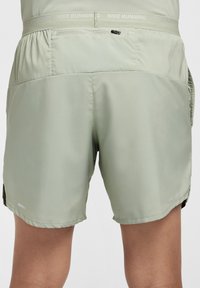 Calções de corrida Nike verde claro com cintura em malha, bolso traseiro com fecho éclair e detalhes refletores na bainha.