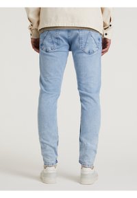 Ljust blå denimjeans med smal passform, som har två bakfickor och subtila slitningar. Avslutade med en uppvikt nederkant och matchat med vita sneakers.