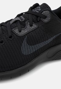 Scarpa sportiva nera con una tomaia in tessuto testurizzato, dotata di un logo Nike a forma di swoosh riflettente in nero e un collare imbottito per supporto.