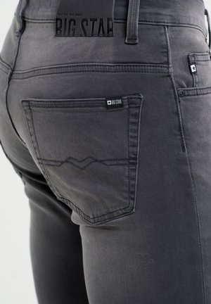 Jeans in denim grigio con vestibilità slim, una tasca posteriore visibile con etichetta logo e dettagli di cucitura sottili. Etichetta in gomma sulla vita inclusa.