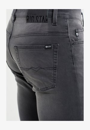 Jeans in denim grigio con vestibilità slim, una tasca posteriore visibile con etichetta logo e dettagli di cucitura sottili. Etichetta in gomma sulla vita inclusa.