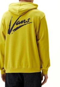 Felpa gialla in morbido tessuto con cappuccio regolabile. Presenta un grande logo "Vans" viola sulla schiena. Vestibilità classica con maniche lunghe.