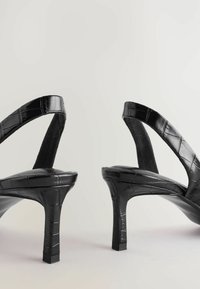 Schwarze Slingback-Absätze mit glänzender Krokodilprägung, spitzer Zehenform und einem Stiletto-Absatz für eine elegante Silhouette.