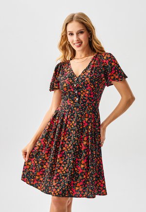 Schwarzes Blumenkleid mit kurzen Puffärmeln, verziert mit lebhaften roten, pinken und orangefarbenen Blumen, einem V-Ausschnitt und einer Knopfverzierung vorne.