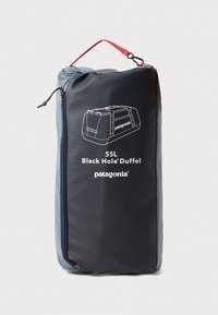 Patagonia 55L Black Hole Duffel, črna tkanina s teksturiranim zaključkom, ima rdeč trak, zadrgo in belo grafiko logotipa.