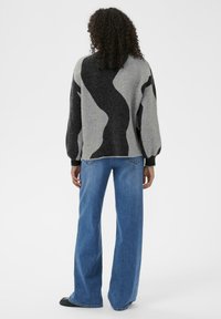 Gray and black patterned sweater with puffed sleeves, paired with fitted blue jeans. The texture of the sweater appears soft and knitted.
