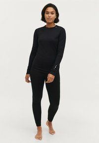 Zwarte lange mouwen top en leggings van rekbaar materiaal. De top heeft een ronde halslijn en een minimalistisch ontwerp met subtiele branding op de mouwen.