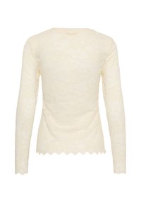 Haut en dentelle crème à manches longues vu de dos, avec un motif floral délicat et un ourlet festonné.